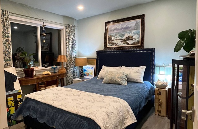 Bedroom with a navy headboard beneath a framed seascape painting