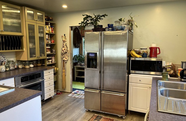Full kitchen with glass-front cabinets, a large fridge, and open pantry shelving